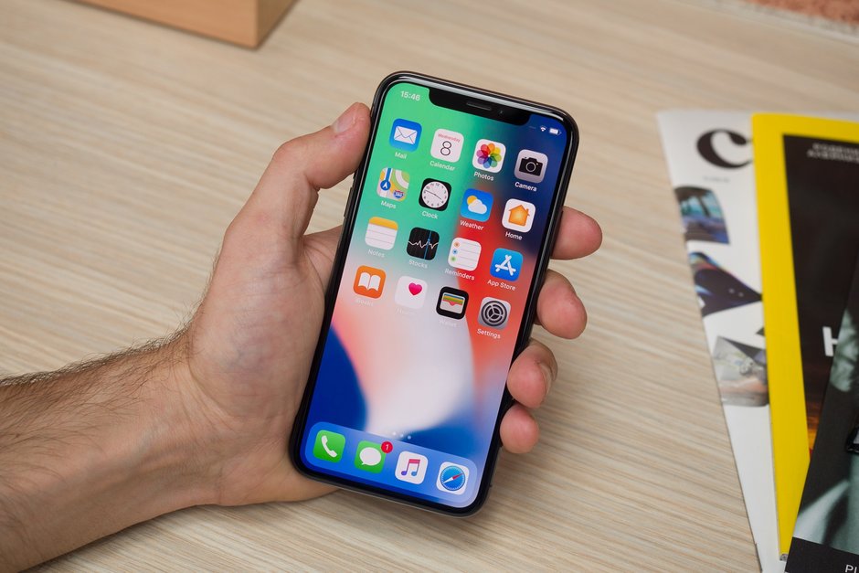Tampilan menu di iPhone X hitam yang digenggam oleh seorang pria